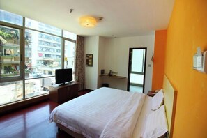 A hotel room with a large window, a bed, a TV on a wooden cabinet, and a mirror on the wall. - Makeboat Hotel (Zhuhai Lovers Road Riyuebei Branch) (Zhuhai)