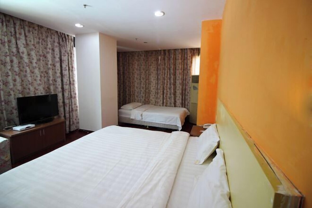 A hotel room with a bed, a TV, and a small desk.