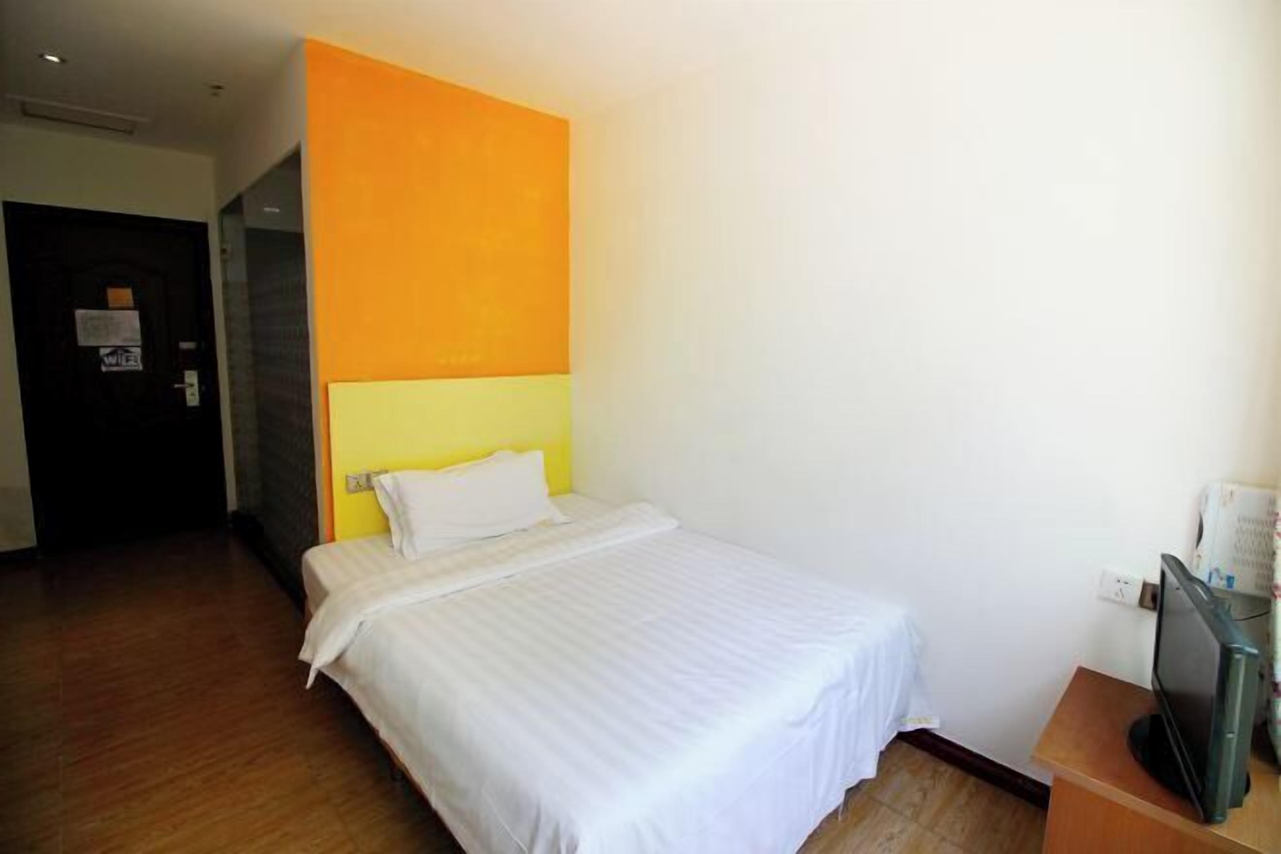 A hotel room with a bed, a television, and a door.