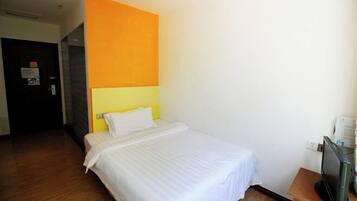 A hotel room with a bed, a television, and a door.