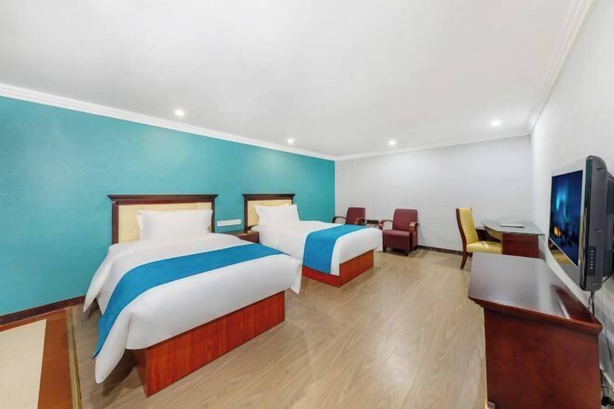 Une chambre d’hôtel avec deux lits, un bureau, une chaise et un téléviseur.