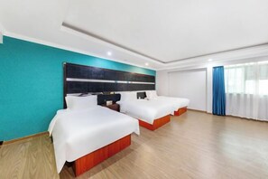 Quarto de hotel com duas camas, parede decorada em tom de verde-água e uma janela grande com cortinas.