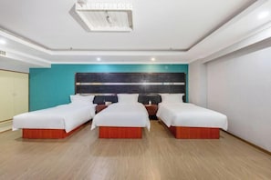 Quarto de hotel com três camas de solteiro, uma janela grande e um design moderno no teto.