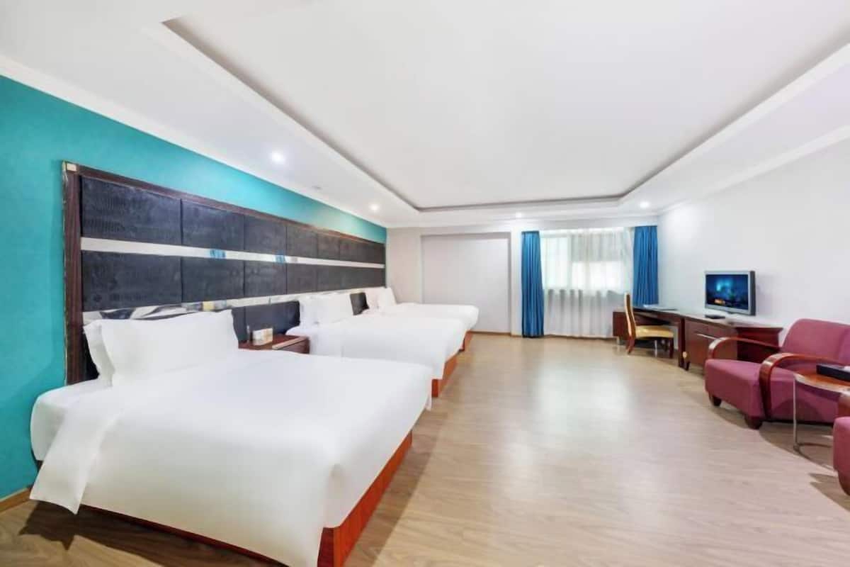 Une chambre d’hôtel avec deux lits, un bureau, une télévision et un coin salon.