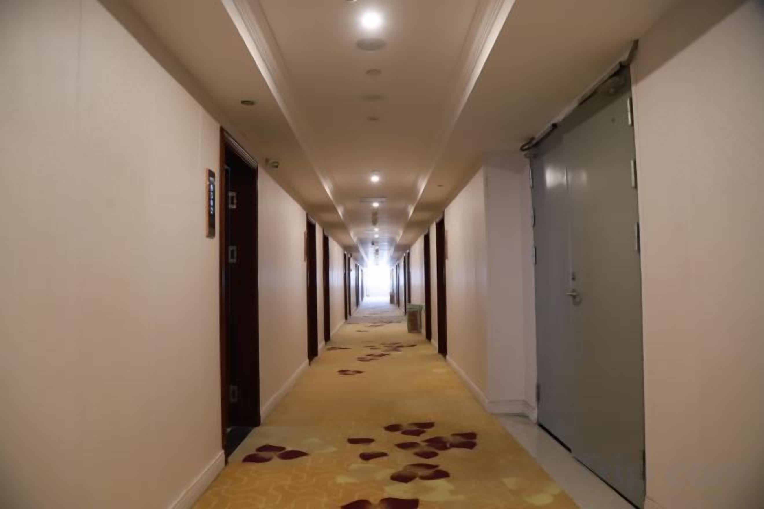 Passadís d'hotel amb portes a ambdós costats, sòl amb moqueta i un llarg corredor que condueix a una porta al final.