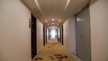 Passadís d'hotel amb portes a ambdós costats, sòl amb moqueta i un llarg corredor que condueix a una porta al final.