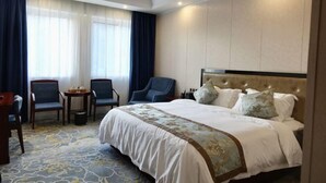 A hotel room with a large bed, two chairs, a small table, and a window with curtains. - Impression Nanlin Hotel (Nanping)