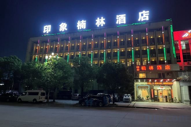 A hotel with a modern facade, illuminated signage, and a parking area in front.