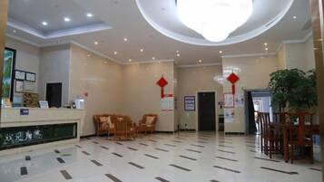 A hotel lobby with a reception desk, seating area, and a large chandelier.