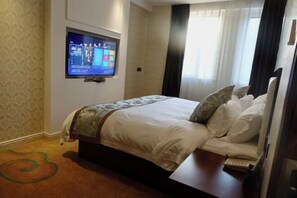 A hotel room with a bed, a television mounted on the wall, a telephone, and a carpet with a green design. - Impression Nanlin Hotel (Nanping)