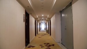 A long, narrow hallway with a carpeted floor and a series of doors on one side. - Impression Nanlin Hotel (Nanping)