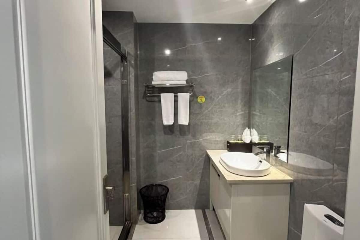 A modern bathroom with a marble wall, a sink, a mirror, and a towel rack.