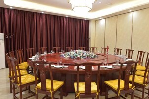 Un salón de conferencias con una mesa redonda, sillas y un candelabro.