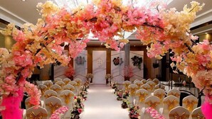 A hotel interior with a floral archway, rows of white chairs with gold bows, and a marble floor. - Lan Tian Business Hotel (Wuyang)