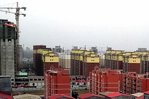 A construction site with multiple buildings under development, featuring a mix of red and yellow facades.