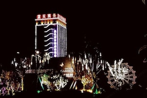 Un edificio con letreros iluminados y una noria.