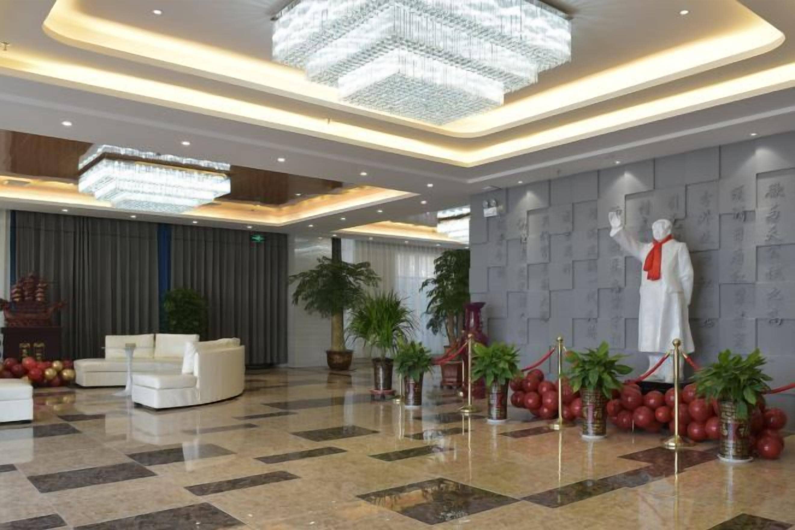 Un vestíbulo con candelabro, estatua y plantas en macetas.