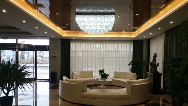 A lobby with a round seating area, a chandelier, and potted plants. - Lan Tian Business Hotel (Wuyang)