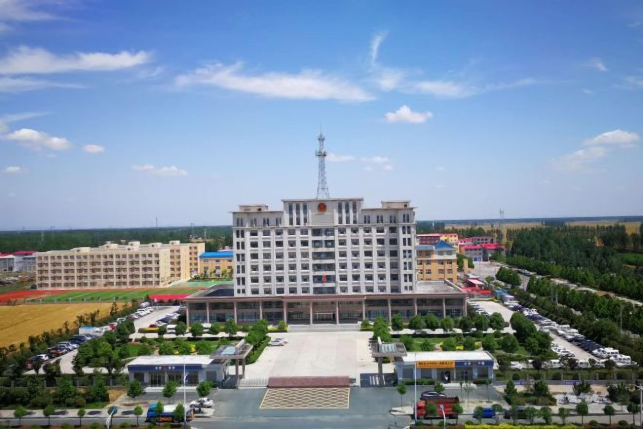 A multi-story building with a central courtyard, surrounded by parking and greenery.