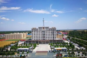 A multi-story building with a central courtyard, surrounded by parking and greenery. - Lan Tian Business Hotel (Wuyang)