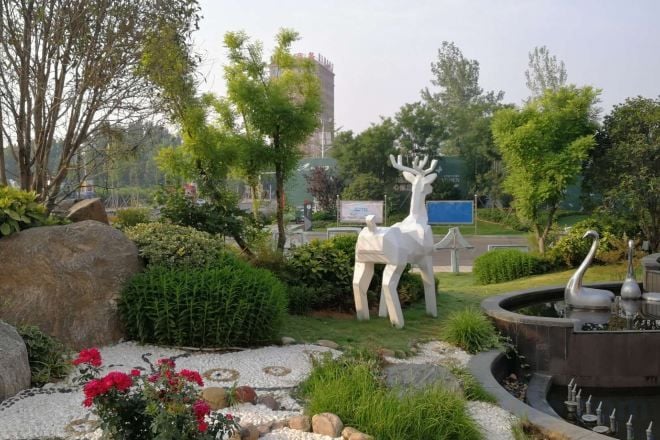 A landscaped garden with a fountain, a deer statue, and a pond.