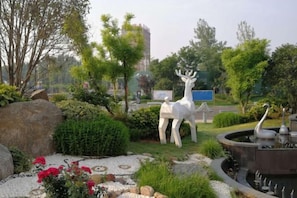 A landscaped garden with a fountain, a deer statue, and a pond.