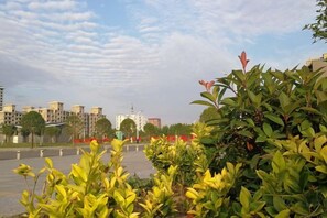 A courtyard with greenery, a clear sky, and buildings in the background. - Lan Tian Business Hotel (Wuyang)