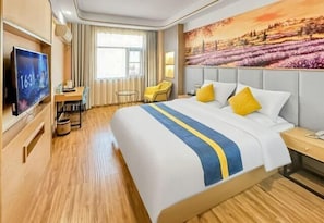 A hotel room with a large bed, a desk, a chair, a TV, and a painting on the wall. - Lan Tian Business Hotel (Wuyang)