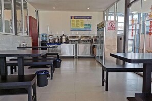 A restaurant interior with tables, chairs, a counter, and a menu on the wall.