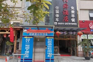 A hotel entrance with a traditional Chinese architectural style, featuring a red roof and a signboard with contact information. - Bojuejioudian (Daozhen)