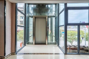 A hotel lobby with a glass elevator, large windows, and a tiled floor. - Bojuejioudian (Daozhen)