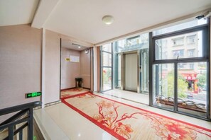 A hotel corridor with a carpet, a glass door, and a view of the outside.