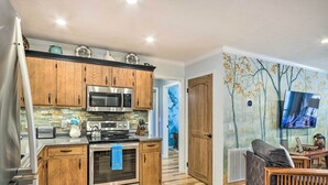 Une cuisine moderne avec des meubles en bois, des appareils électroménagers en acier inoxydable et un parquet en bois disposé en chevrons.