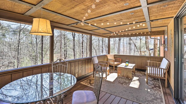 Une terrasse en bois avec une table en verre, des chaises et des lampes suspendues.