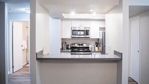 Una cocina moderna con armarios blancos, electrodomésticos de acero inoxidable y una isla central.