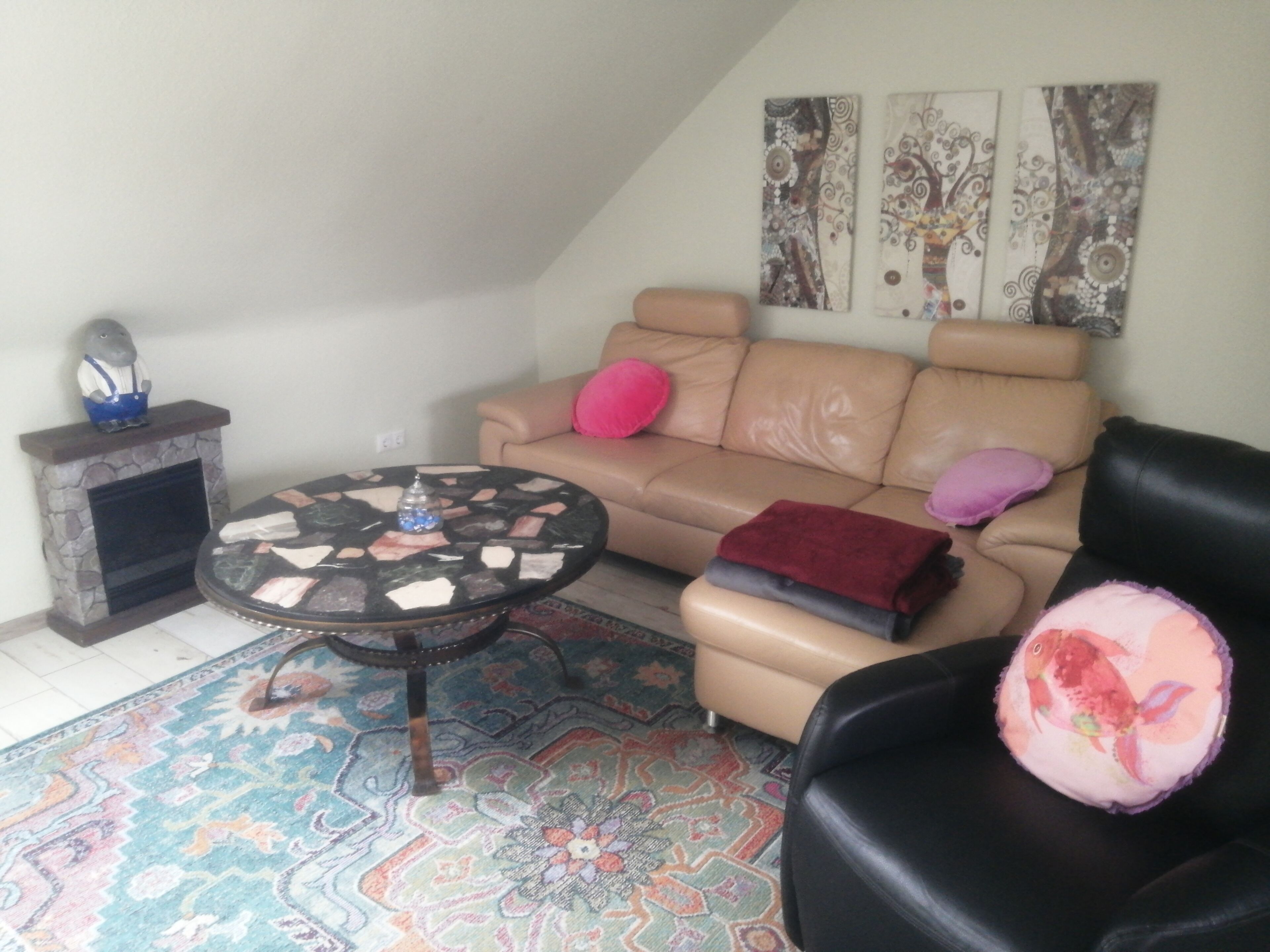 Un salon comprenant un canapé, une table basse, une cheminée et un tapis à motifs.