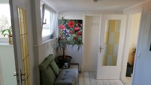 A cozy room with a sofa, a potted plant, and a door with a nameplate. - Apartment (Castrop-Rauxel)