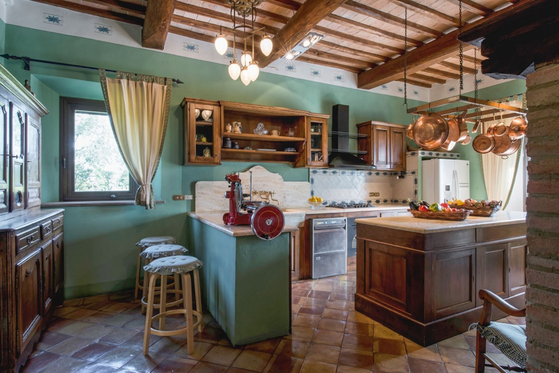 Une cuisine rustique avec des meubles en bois, un poêle d’époque et des casseroles en cuivre suspendues.