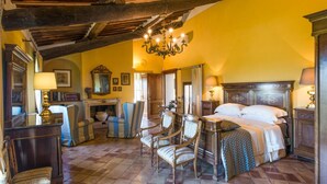 Una habitación tradicional con cama, sillas, chimenea y candelabro.