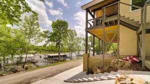 Een modern huis met een overdekt terras, een oprit van beton en uitzicht op een meer met boten.