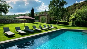 A swimming pool with lounge chairs and a stone wall. - Wonderful Villa in the heart of Chianti (Greve in Chianti)