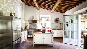 A kitchen with stainless steel appliances, a central island, and a wooden ceiling. - Wonderful Villa in the heart of Chianti (Greve in Chianti)