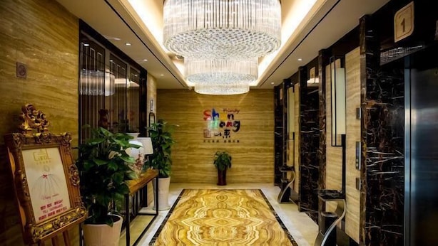 A hotel lobby with a patterned carpet, a chandelier, and a reception desk. - Xikelai Hotel (Qingdao)
