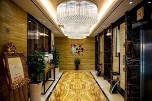 A hotel lobby with a patterned carpet, a chandelier, and a reception desk. - Xikelai Hotel (Qingdao)