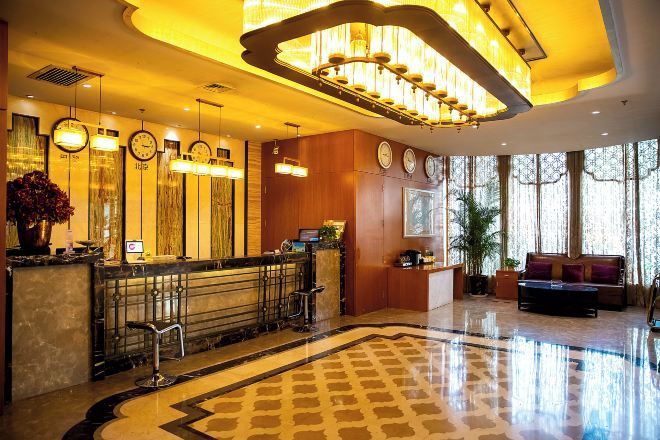 Un vestíbulo de hotel con mostrador de recepción, zona de estar y ventanas amplias.