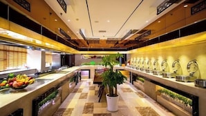 A modern hotel lobby with a central seating area, a buffet with various food items, and a decorative plant in the middle. - Xikelai Hotel (Qingdao)