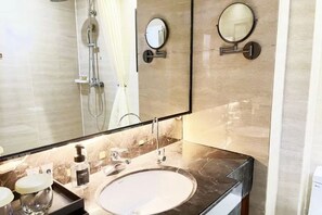 A modern bathroom with a large mirror, a sink, and a shower. - Xikelai Hotel (Qingdao)