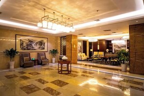 A hotel lobby with a checkered floor, seating area, and a large painting. - Xikelai Hotel (Qingdao)