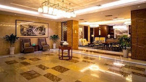 A spacious lobby with a marble floor, a large painting, seating areas, and a chandelier. - Xikelai Hotel (Qingdao)