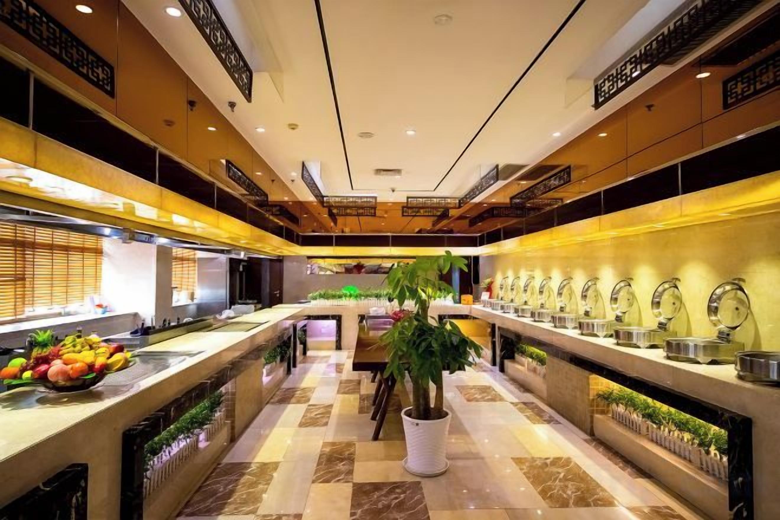 Un vestíbulo de hotel con una planta central, una larga recepción y varios relojes en la pared.
